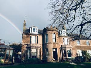 a large brick house with a rainbow in the background at The Limes Guest House in Montrose