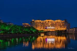 Grand Metropark Longxi Conference Center Beijing في بكين: فندق وانعكاسه في الماء ليلا
