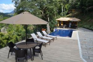 a patio with chairs and an umbrella and a pool at Vaca do Brejo, piscina aquecida, sauna, A/C quente in Petrópolis