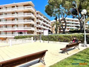 eine Person, die auf einer Bank vor einem Gebäude sitzt in der Unterkunft APARTBEACH CYE 6 CLIMATIZADO y JUNTO PLAYA in Salou