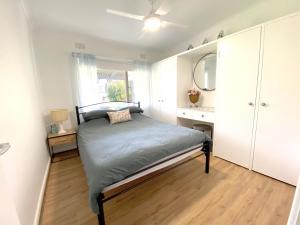 Schlafzimmer mit einem Bett, einer Kommode und einem Spiegel in der Unterkunft Minto Merimbula in Merimbula