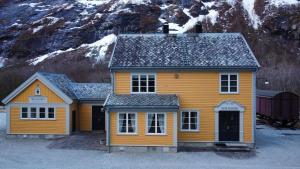 a yellow house in front of a snow covered mountain at Trollveggen Stasjon in Åndalsnes
