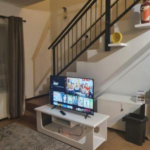 uma televisão sentada numa mesa branca debaixo de uma escada em Cosy, stylish, 2 bed apartment, free wifi, Netflix, dstv now em Midrand