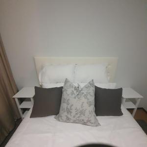 uma cama branca com almofadas em cima em Cosy, stylish, 2 bed apartment, free wifi, Netflix, dstv now em Midrand