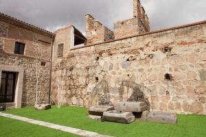 - un vieux bâtiment avec une cour verdoyante à côté dans l'établissement Sofraga Palacio, World Hotels Crafted, à Ávila