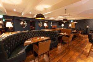 um restaurante com um sofá de couro e mesas e cadeiras em Best Western Plus White Horse Hotel em Derry Londonderry