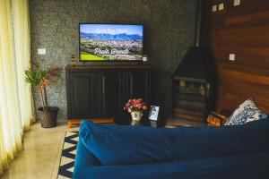 uma sala de estar com um sofá azul e uma televisão em Canyons Guest House em Praia Grande