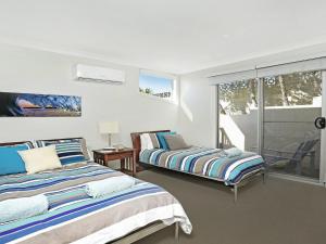 a bedroom with two beds and a balcony at Santa Barbara on Bombo Beach in Kiama