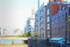 a river in a city with buildings and a bridge at Sakuragawa River Side Hotel in Osaka