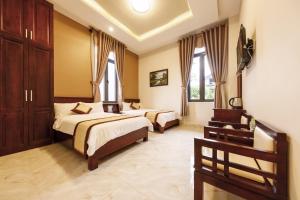 1 dormitorio con 2 camas y 2 ventanas en Bonjour Da Lat Hotel en Dalat