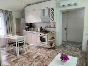 a kitchen with white cabinets and a table with purple flowers at Seaside Apartment Batumi Beach in Batumi
