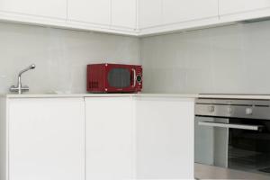 a red microwave sitting on top of a kitchen counter at GuestReady - West Kensington Home wBalcony in London