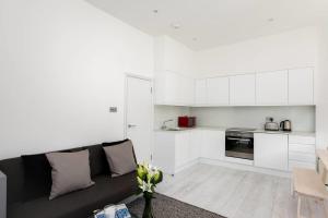 a living room with a couch and a kitchen at GuestReady - West Kensington Home wBalcony in London