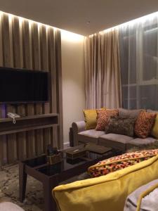 sala de estar con sofá y TV de pantalla plana en Lavender Hotel, en Taif