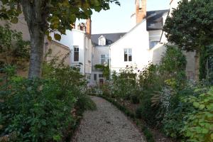 un camino de jardín frente a una casa blanca en Room in Guest room - This 10th Century home sits in an extraordinary setting in the center of Orleans en Orléans