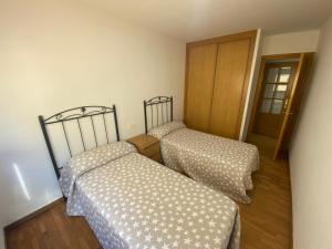 duas camas num pequeno quarto com uma porta em Piso céntrico, con amplia terraza, 3 dormitorios em Ribeira