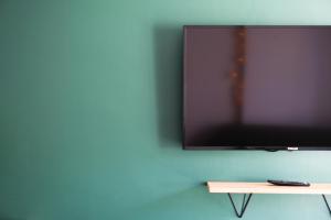 uma televisão de ecrã plano pendurada numa parede azul em Le Chambord 2 em Laval
