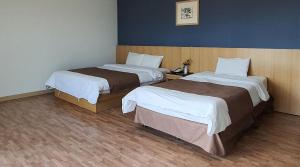 two beds in a hotel room with two beds at Blue Hawaii Resort in Jeju