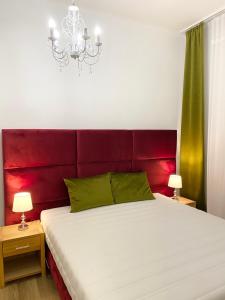 una camera con un grande letto con testiera rossa di Platános Apartman Tata a Tata