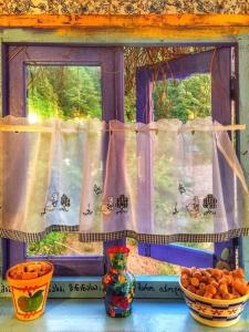 una ventana con cortinas y cuencos de fruta sobre una mesa en Cottage Chalet in Kvariati, en Kvariat'i