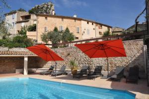 two red umbrellas and chairs next to a swimming pool at Les Terrasses de la Roque-Alric in La Roque-Alric