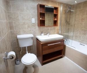 a bathroom with a toilet and a sink and a tub at The Sun Inn At Hook Norton in Banbury