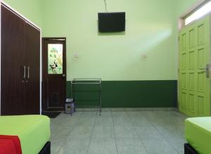 a room with two green doors and a television on the wall at Cantik Hotel in Bandung