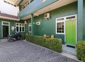 a motorcycle parked outside of a building with a green door at Cantik Hotel in Bandung