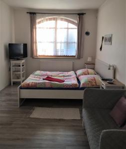 - une chambre avec un lit, un canapé et une fenêtre dans l'établissement Ubytování Pod lázněmi Klimkovice, à Klimkovice