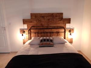 Bett mit einem Kopfteil aus Holz in einem Zimmer in der Unterkunft La Gurlanne in Lasséran