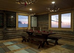a dining room with a table and benches and windows at Polar Lights Lodge in Sirkka