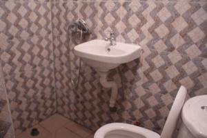 La salle de bains est pourvue d'un lavabo et de toilettes. dans l'établissement HOTEL-LE-PARISIEN, à Brazzaville