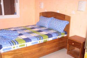 uma cama com uma moldura de madeira e almofadas azuis em HOTEL-LE-PARISIEN em Brazavile
