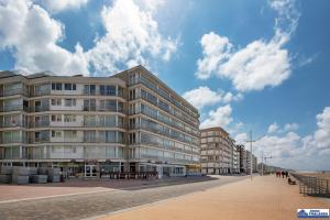 a building on the beach with people walking in front of it at Atlantic 0504 in Koksijde