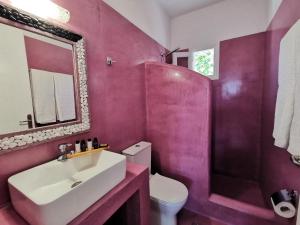 a pink bathroom with a sink and a toilet at Family Villages Santorini in Vlychada Beach