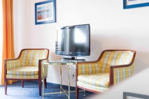 a room with two chairs and a tv on a table at Pension Auszeit in Langenargen