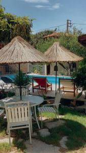 a table and chairs with umbrellas next to a pool at Akropolis Guest House in Bergama