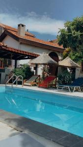 a swimming pool with two chairs and umbrellas next to a house at Akropolis Guest House in Bergama