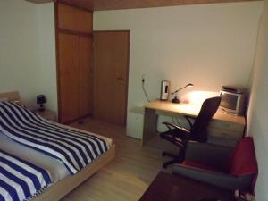 Schlafzimmer mit einem Bett und einem Schreibtisch mit einem Computer in der Unterkunft Private Übernachtung in Kempten