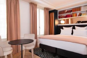 - une chambre avec un grand lit, une table et des chaises dans l'établissement Hotel Louvre Montana, à Paris