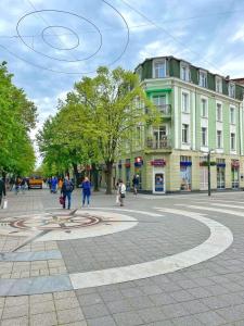 a group of people walking on a street with a building at Апартамент Компас in Burgas City