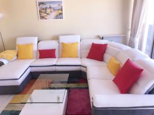 a living room with a white couch with colorful pillows at Rue Roland Garros in Fréjus