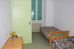 Habitación con 2 camas, mesa y puerta en Chambres d'Hôtes Le Clos Ambels, en Ambialet