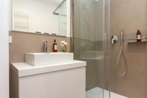 La salle de bains est pourvue d'un lavabo blanc et d'une douche. dans l'établissement Yourbanflat Chic Voyage, à Padoue