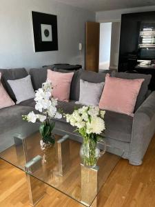 a living room with a couch and vases of flowers at Shorthorn Apartment, 53a Sea Road in Carlyon Bay