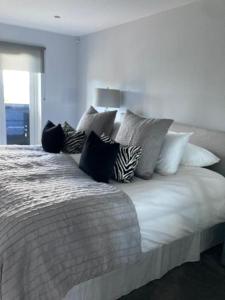a large white bed with many pillows on it at Shorthorn Apartment, 53a Sea Road in Carlyon Bay