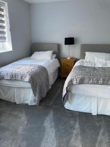 a bedroom with two beds and a table with a lamp at Shorthorn Apartment, 53a Sea Road in Carlyon Bay