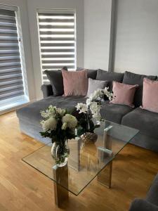 a living room with a couch and a glass table with flowers at Shorthorn Apartment, 53a Sea Road in Carlyon Bay