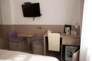 a hotel room with a desk and a tv on the wall at Mini ELEGANT in Kyiv
