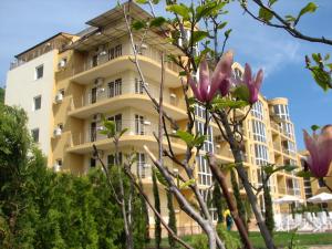 un bâtiment avec des fleurs roses devant lui dans l'établissement Joya Park Apartments, aux Sables d'or
